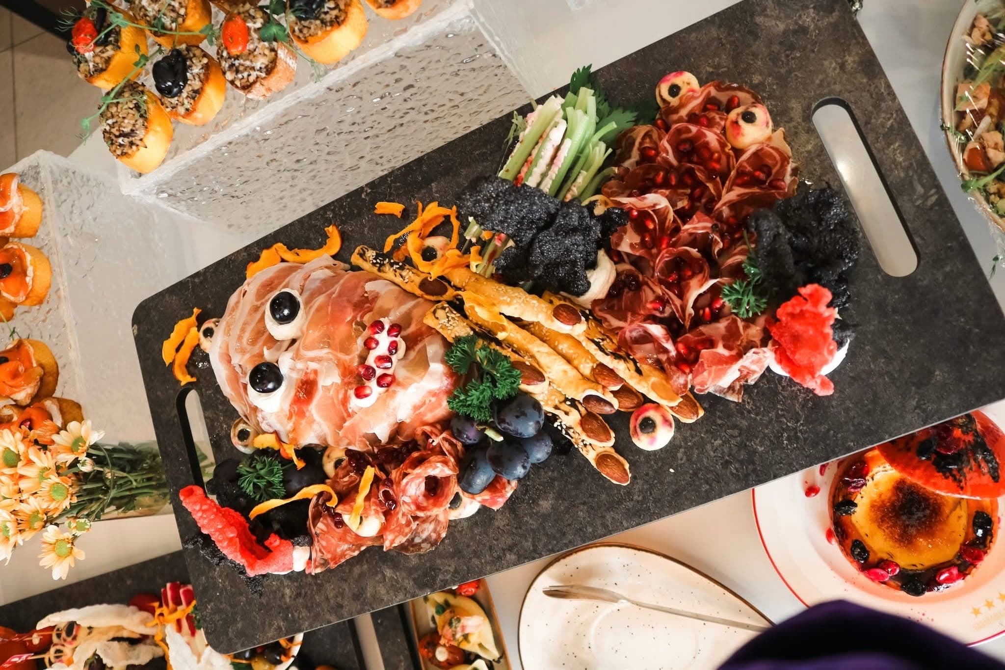 A Halloween buffet platter arranged as a playful skeleton with charcuterie, vegetables and bread.
